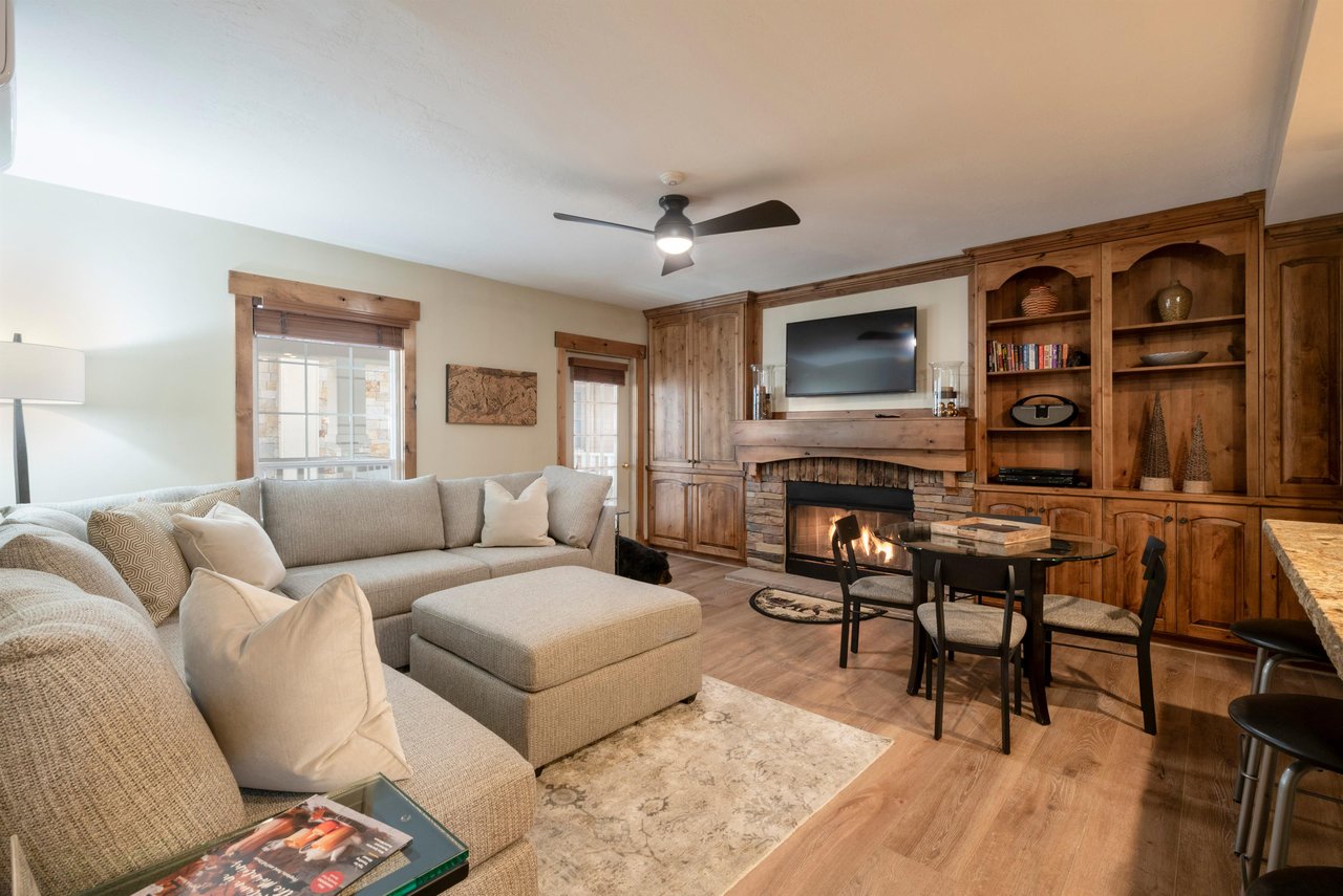 Cozy up by the fireplace in Resort Plaza 5002 — your perfect Park City vacation rental featuring warm wood accents, a spacious sectional, and all the comforts of home after a day on the slopes.