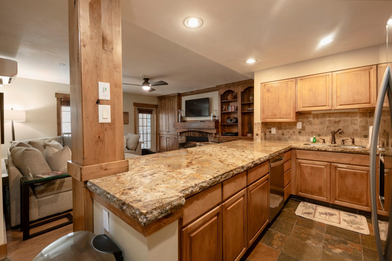 The open kitchen and living area at Resort Plaza 5002 makes entertaining effortless — this Park City lodging features beautiful granite counters, rich wood cabinetry, and a seamless flow perfect for g