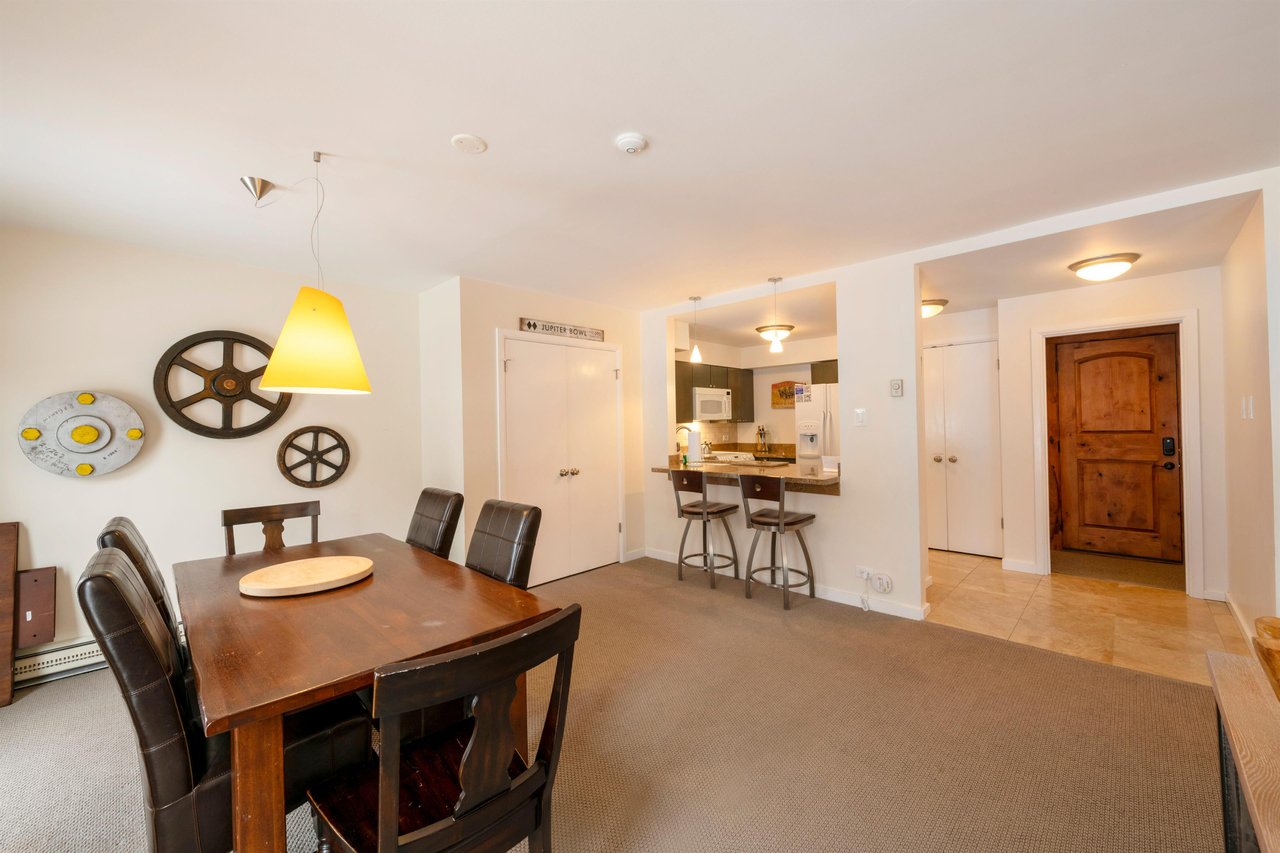 Gather around the warm wood dining table at Resort Plaza 5007 — this inviting Park City vacation rental features a spacious dining area with an open flow into the kitchen and bar seating, perfect for