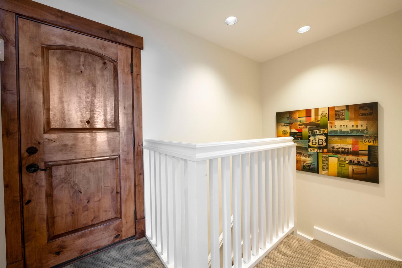 The charming entryway and staircase at Resort Plaza 5007 set the tone for a wonderful stay — this beautifully detailed Park City vacation rental welcomes you with a stunning rustic wood door and brigh
