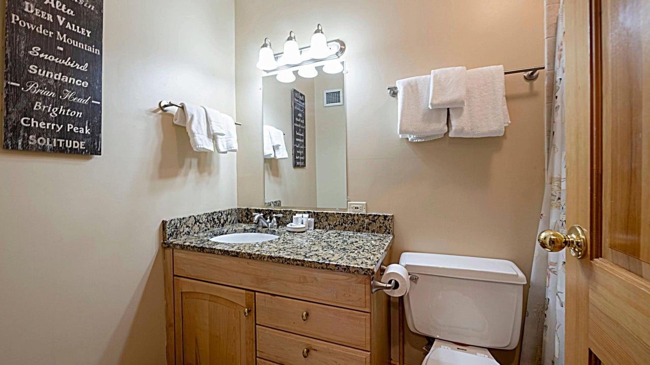 Resort Plaza 5013 features a clean and tastefully finished bathroom with granite countertops and warm wood vanity — a lovely touch in this soughtafter Park City vacation rental.