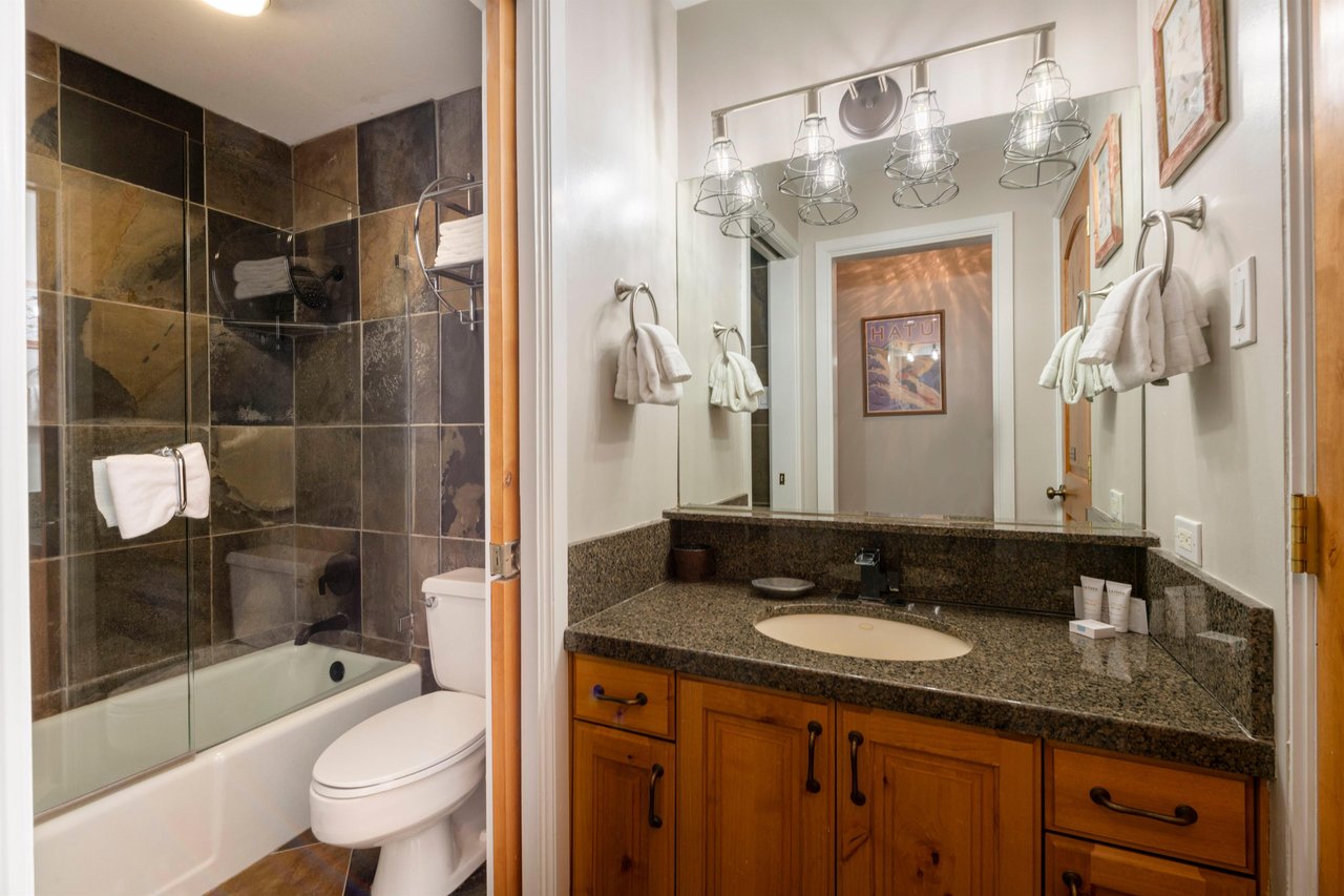 Resort Plaza 5022 features a beautifully tiled bathroom with dark granite countertops and a combination tub and shower — a stylish and functional detail of this Park City vacation rental.