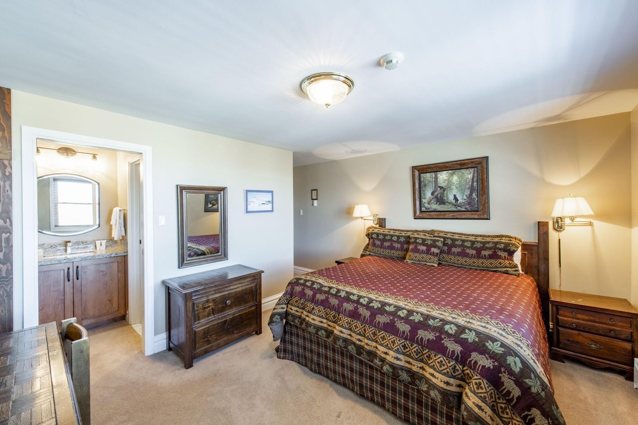 This spacious primary bedroom features warm mountaininspired décor and generous floor space, offering a peaceful and comfortable retreat after a day of adventure. A restful nights sleep awaits at th