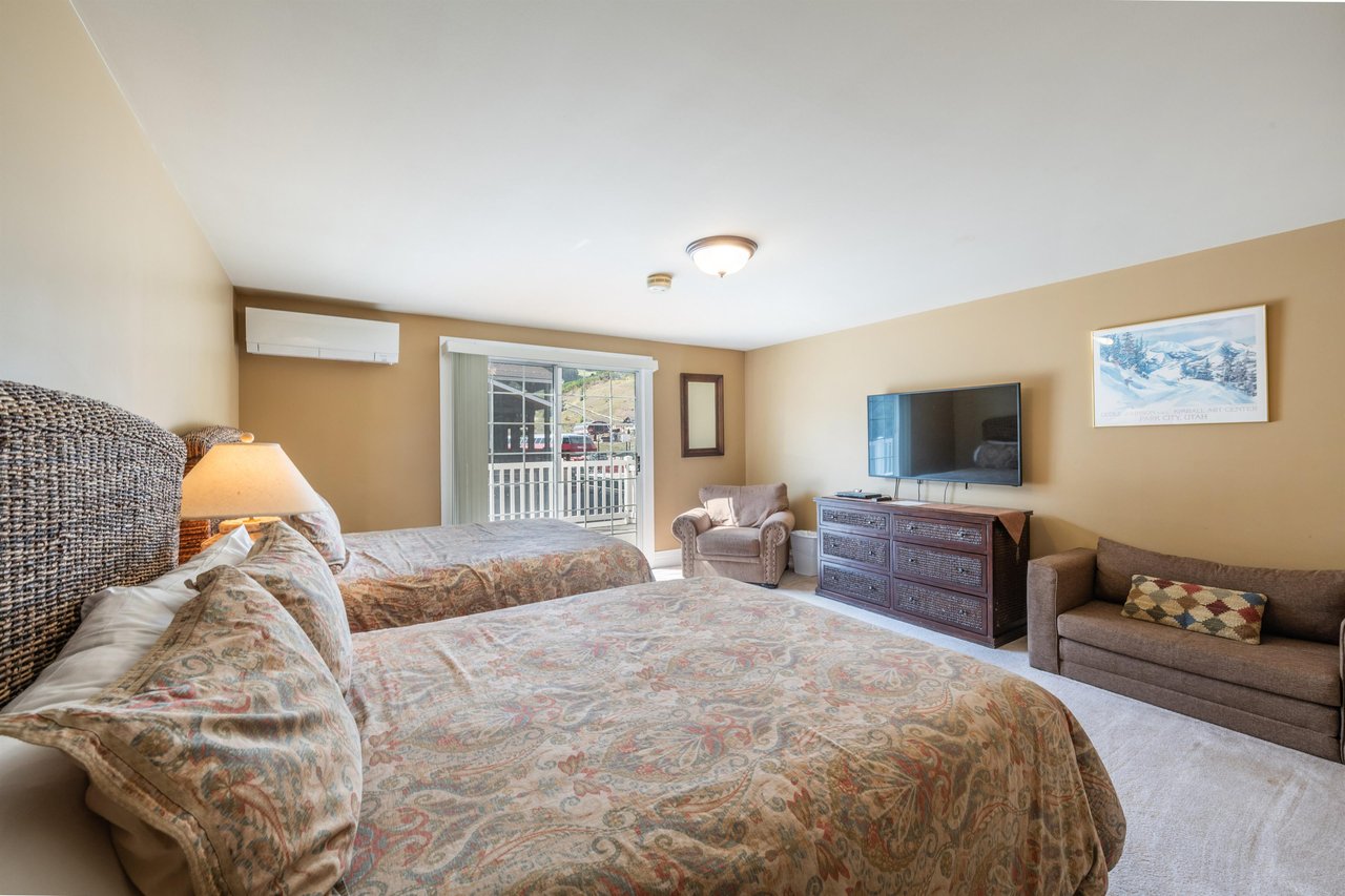 This generously sized double queen bedroom features balcony access, a flatscreen TV, and warm, comfortable furnishings for a relaxing stay. Everything you need for a restful night at this Park City v