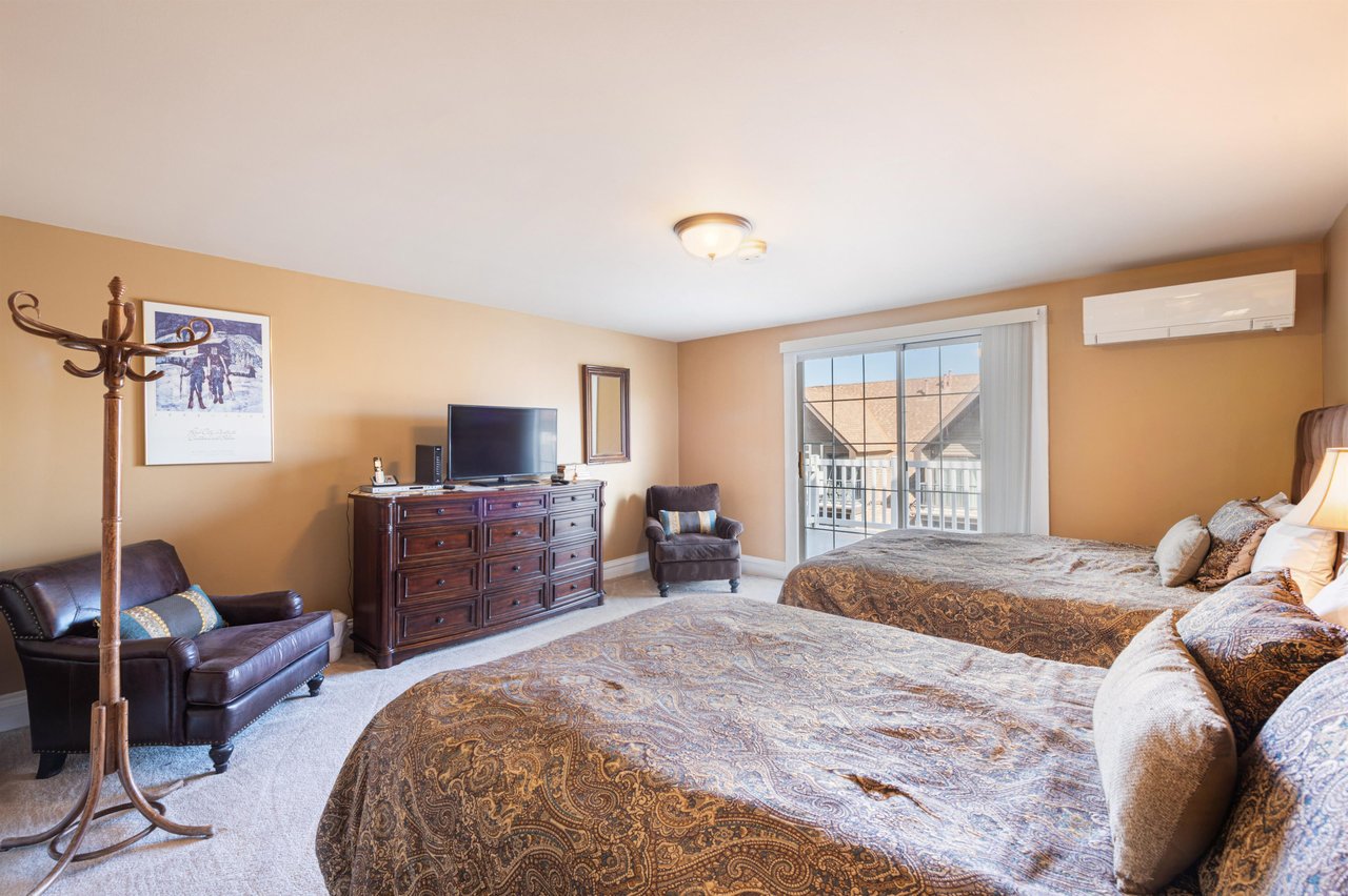 This spacious second bedroom features two queen beds, balcony access, and a flatscreen TV, offering all the comforts needed for a relaxing stay at this Park City vacation rental.