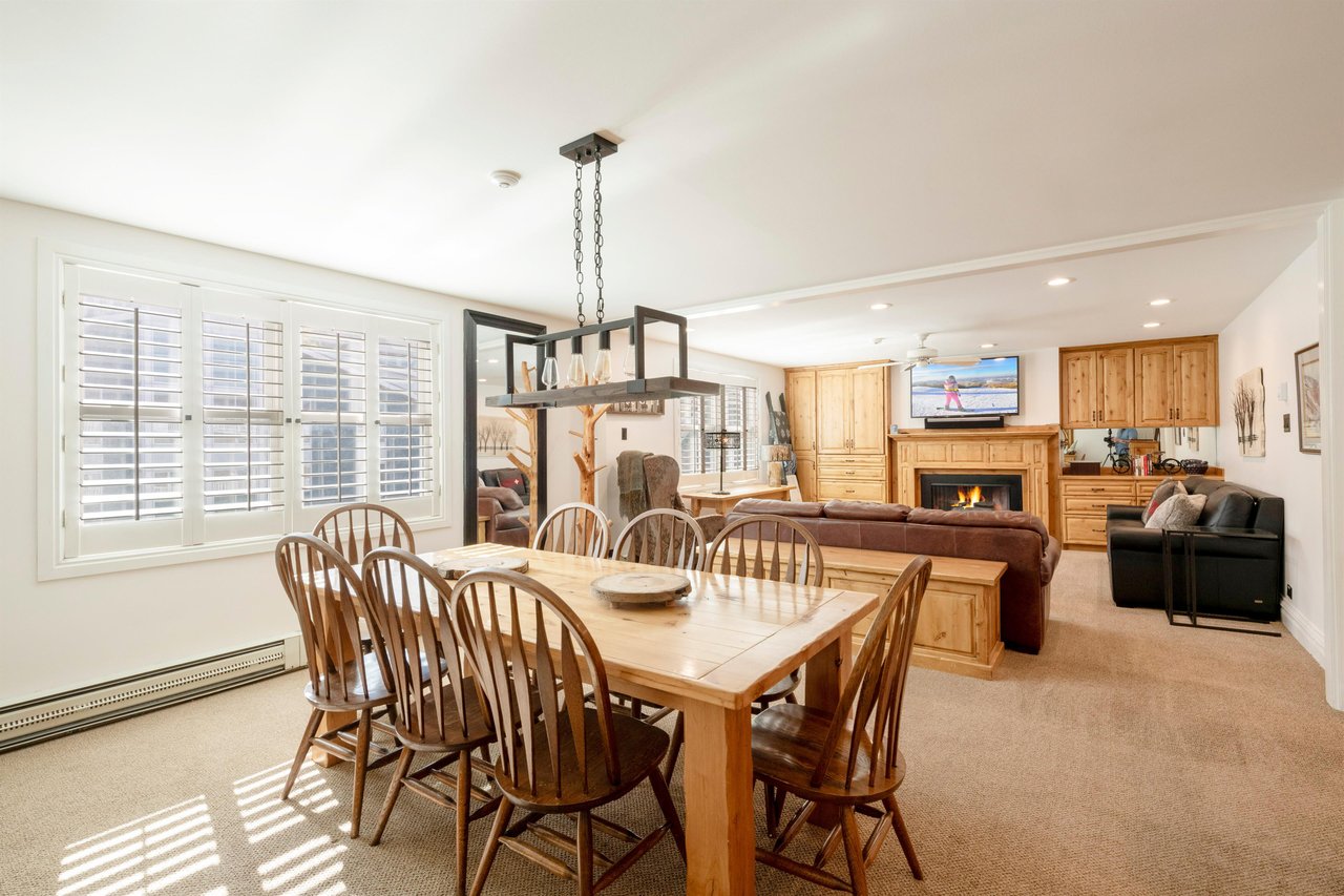 Bathed in natural light, this cheerful dining area offers a large wood table perfect for group meals, with the living room fireplace and flatscreen TV just steps away. A wonderfully connected space w