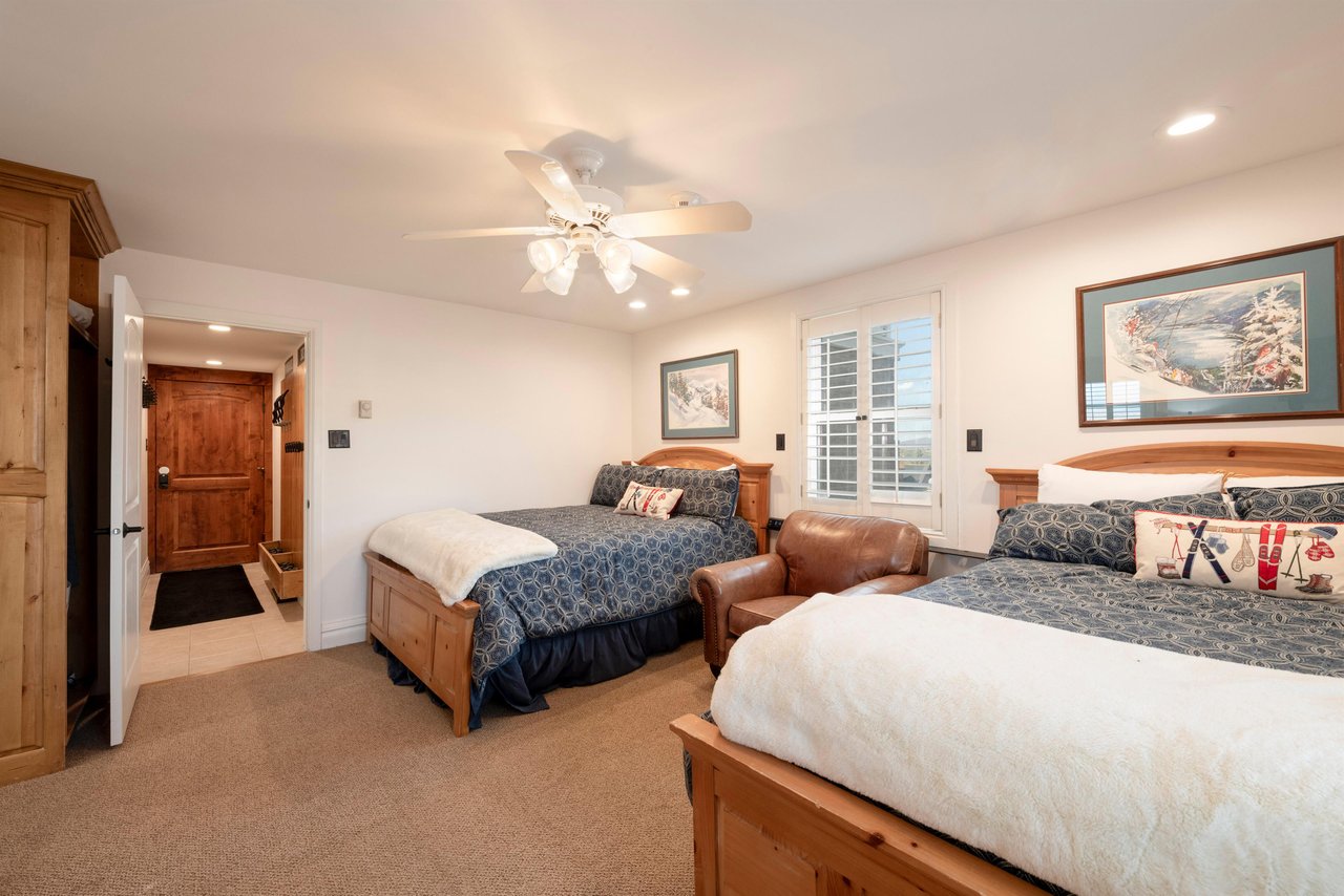 This comfortable double queen bedroom offers warm knotty wood furnishings, classic shuttered windows, and plenty of space for guests to relax and recharge during their Park City vacation rental stay.