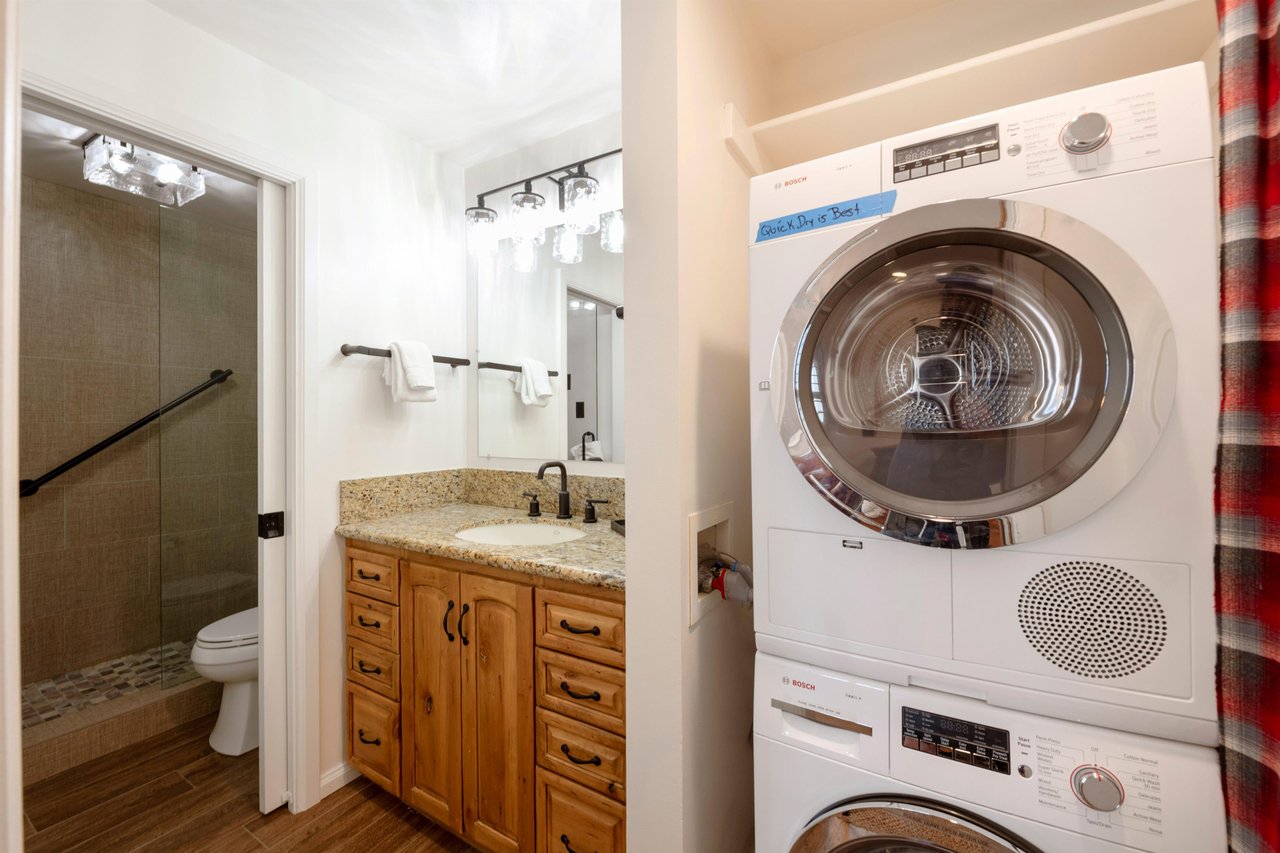 The convenience of an inunit stacked washer and dryer, alongside a wellappointed bathroom with warm wood cabinetry and granite countertops, makes extended stays effortless at this Park City vacation