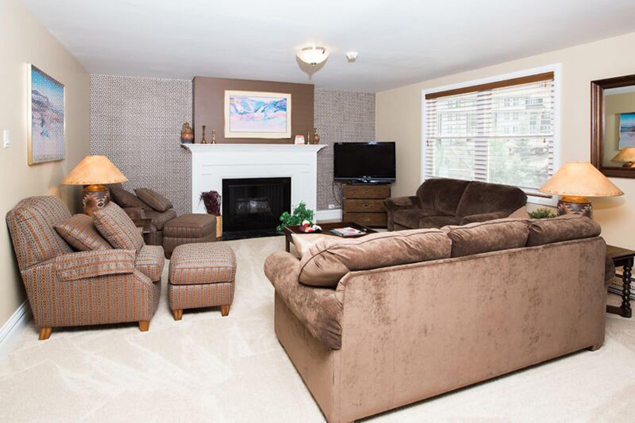 Bright and spacious, this comfortable living room features a classic white fireplace, generous seating, and plenty of natural light for a warm and welcoming atmosphere during your Park City vacation r