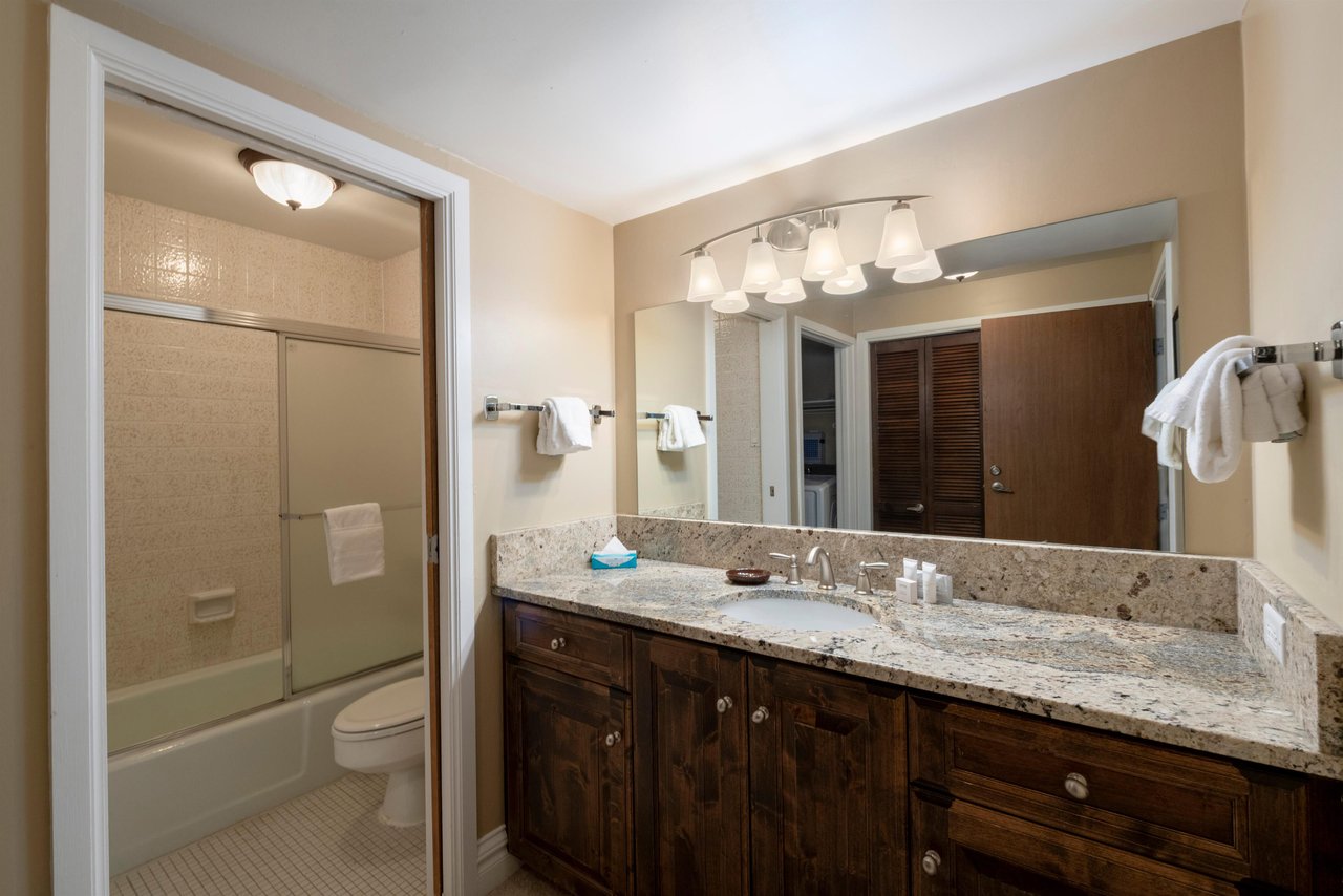 Warm wood finishes, granite countertops, and bright vanity lighting make this guest bathroom a polished and functional space. Consistent quality throughout Resort Plaza 5040 makes it a top choice for