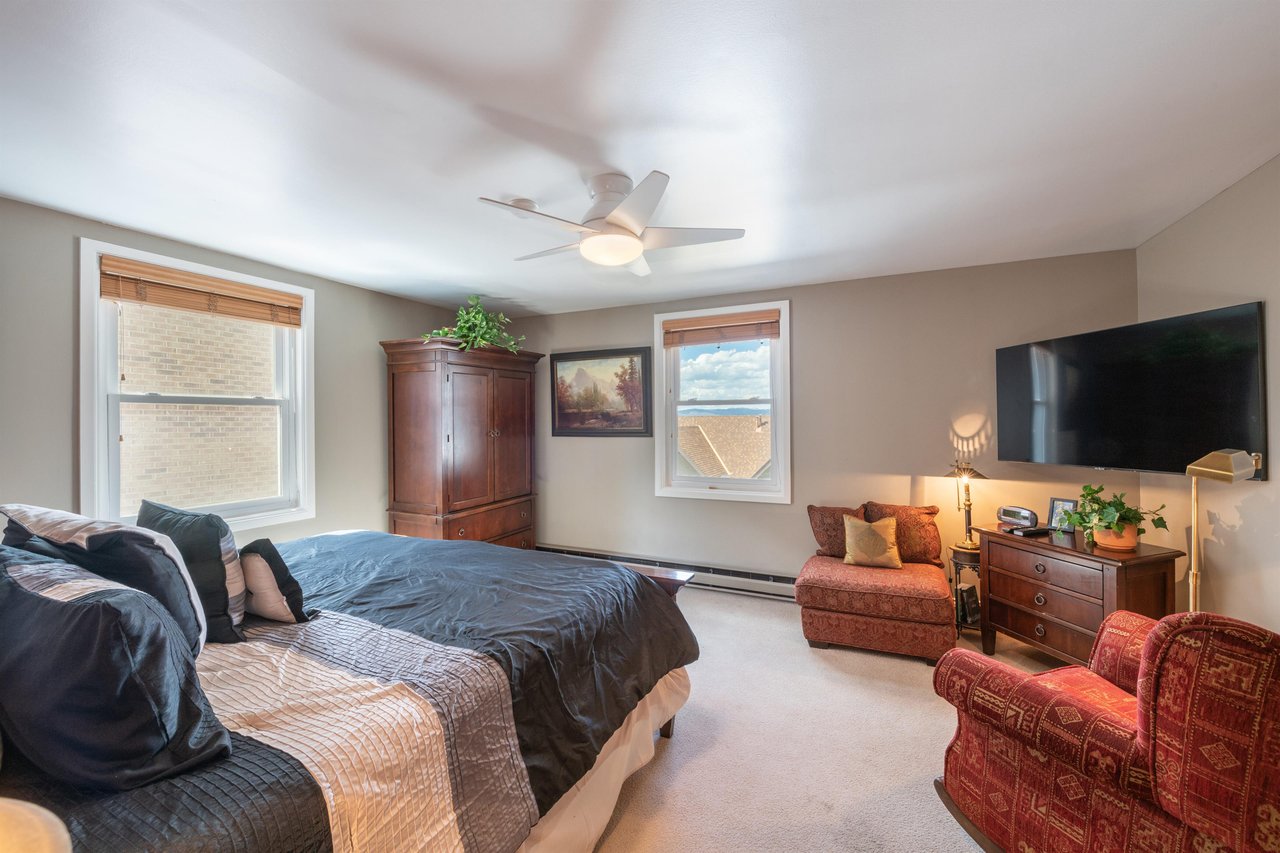 Retire to the spacious and elegantly furnished king bedroom at Resort Plaza 5064, where classic wooden accents, a cozy sitting area, and a wallmounted TV create the perfect sanctuary for a restful ni