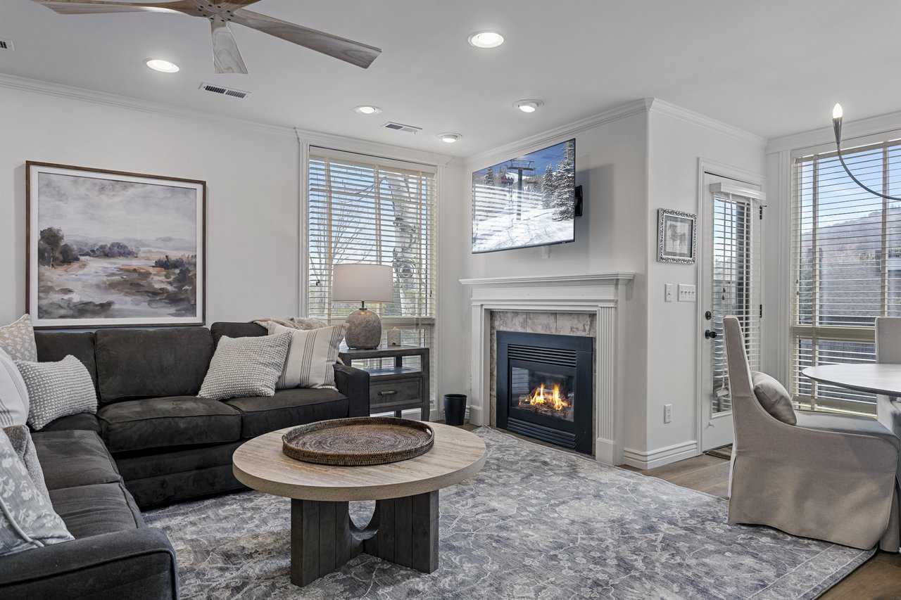 Three Kings 83 welcomes you home with a glowing fireplace, comfortable seating, and bright natural light streaming through oversized windows.
