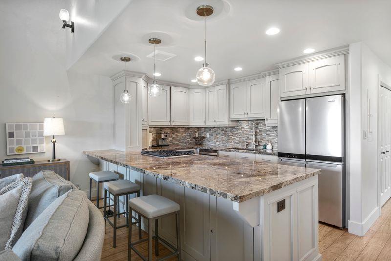 The showstopping kitchen and breakfast bar at Three Kings 64 feature stunning granite countertops, elegant pendant lighting, and premium appliances, creating a sophisticated gathering space that makes