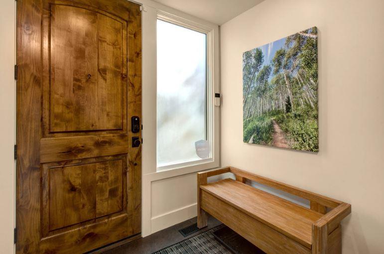 The charming entryway at Three Kings 64 makes a wonderful first impression with its gorgeous knotty wood door and custom builtin bench, offering a practical and inviting welcome to one of Park Citys