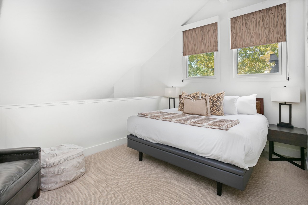 The charming loft king bedroom at Three Kings 64 offers a bright and airy retreat with vaulted ceilings, soft natural light, and cozy furnishings that add a unique and delightful touch to this wonderf