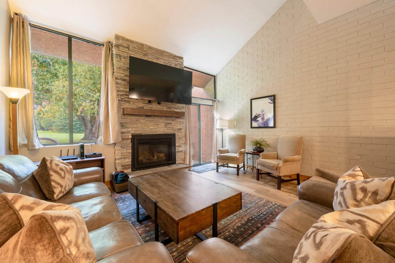 The warm and inviting living room at Park Avenue 256 features a stunning stone fireplace, vaulted ceilings, and comfortable furnishings — a classic mountain retreat that defines quality.