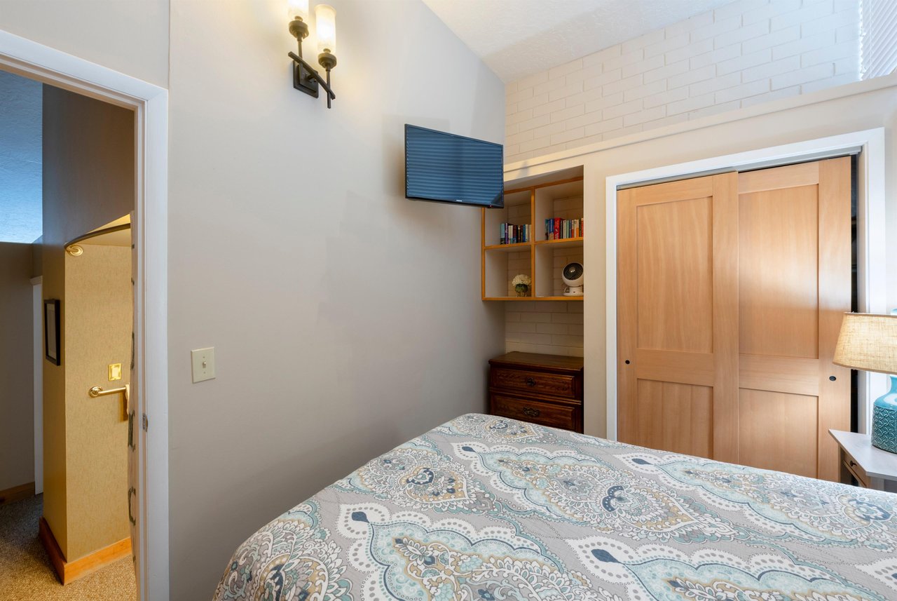 The cozy and efficiently designed bedroom at Park Avenue 256 features builtin shelving, a wallmounted TV, and warm neutral tones — a comfortable and practical sleeping space within this wellappoint