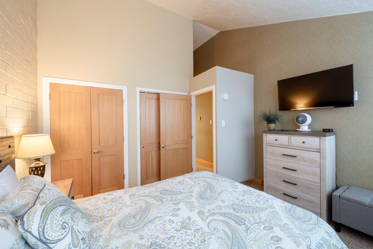 The wellappointed bedroom at Park Avenue 256 features a generous closet for storage, and a wallmounted TV — a comfortable and practical retreat during your stay in Park City.