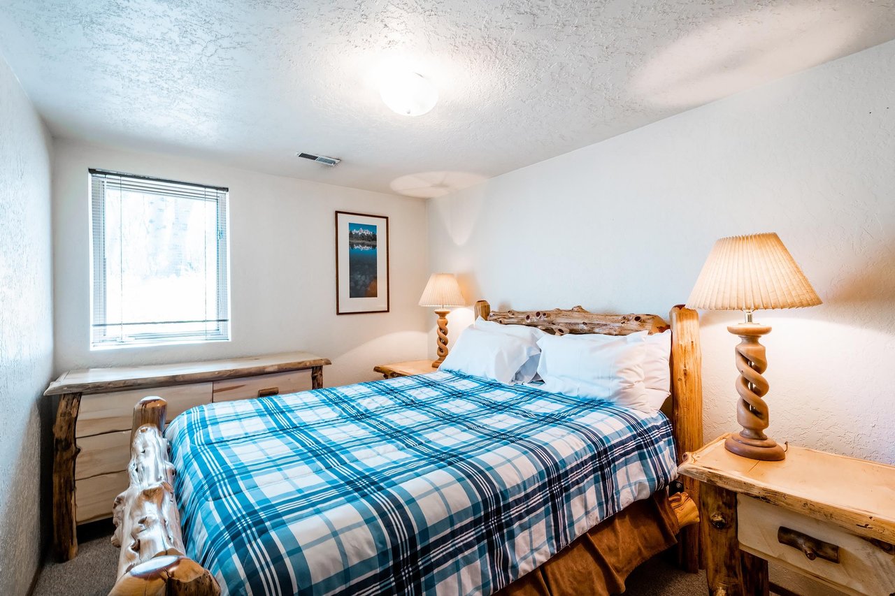 Rest easy in the cozy queen bedroom at Temptation 8, where rustic log furnishings and soft mountaininspired bedding create a warm and inviting retreat at this Park City vacation rental.