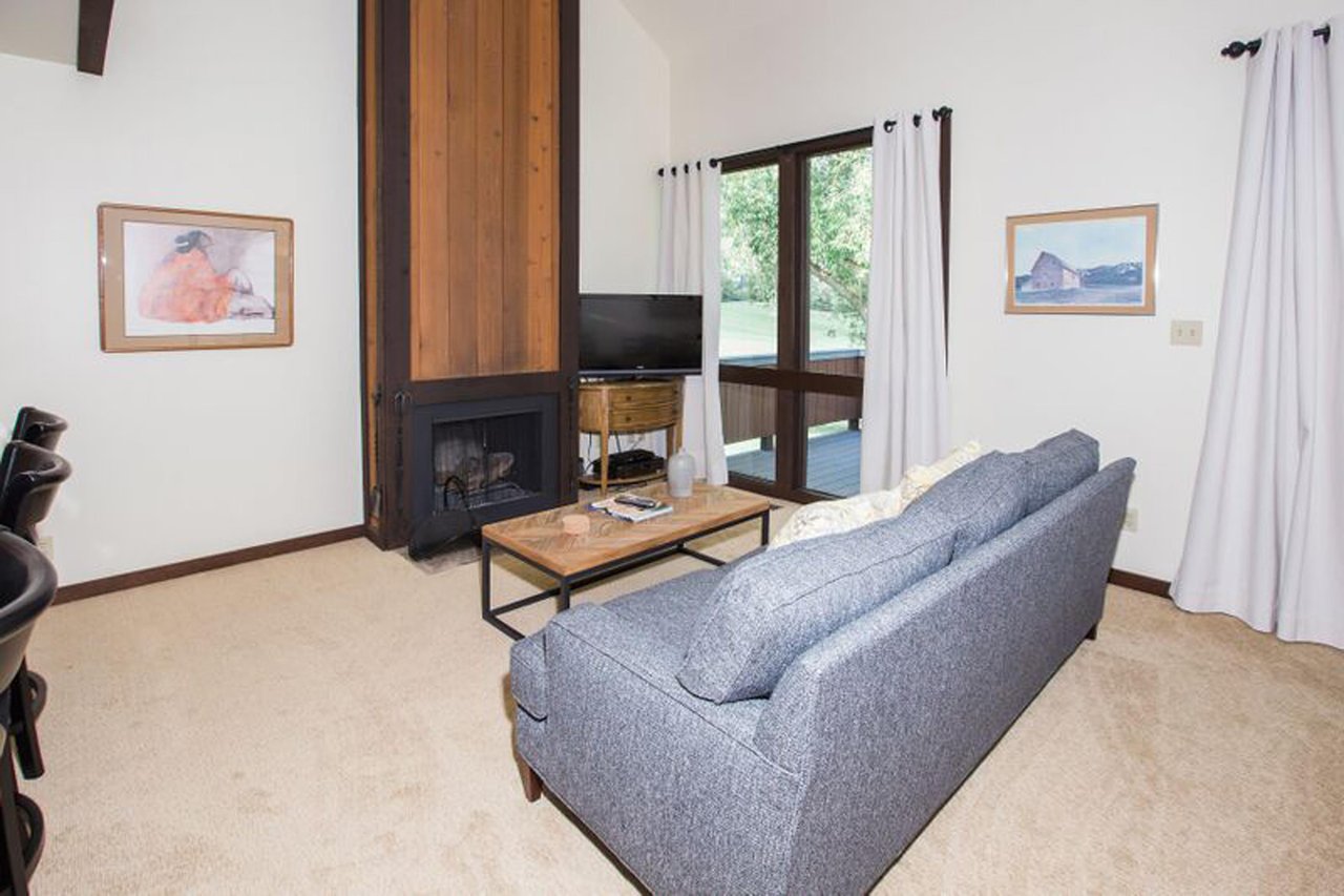 The inviting living room at Three Kings 37 features a comfortable sofa, wood burning fireplace, and easy access to the outdoor deck, making this Park City lodging option the ideal spot to relax and re