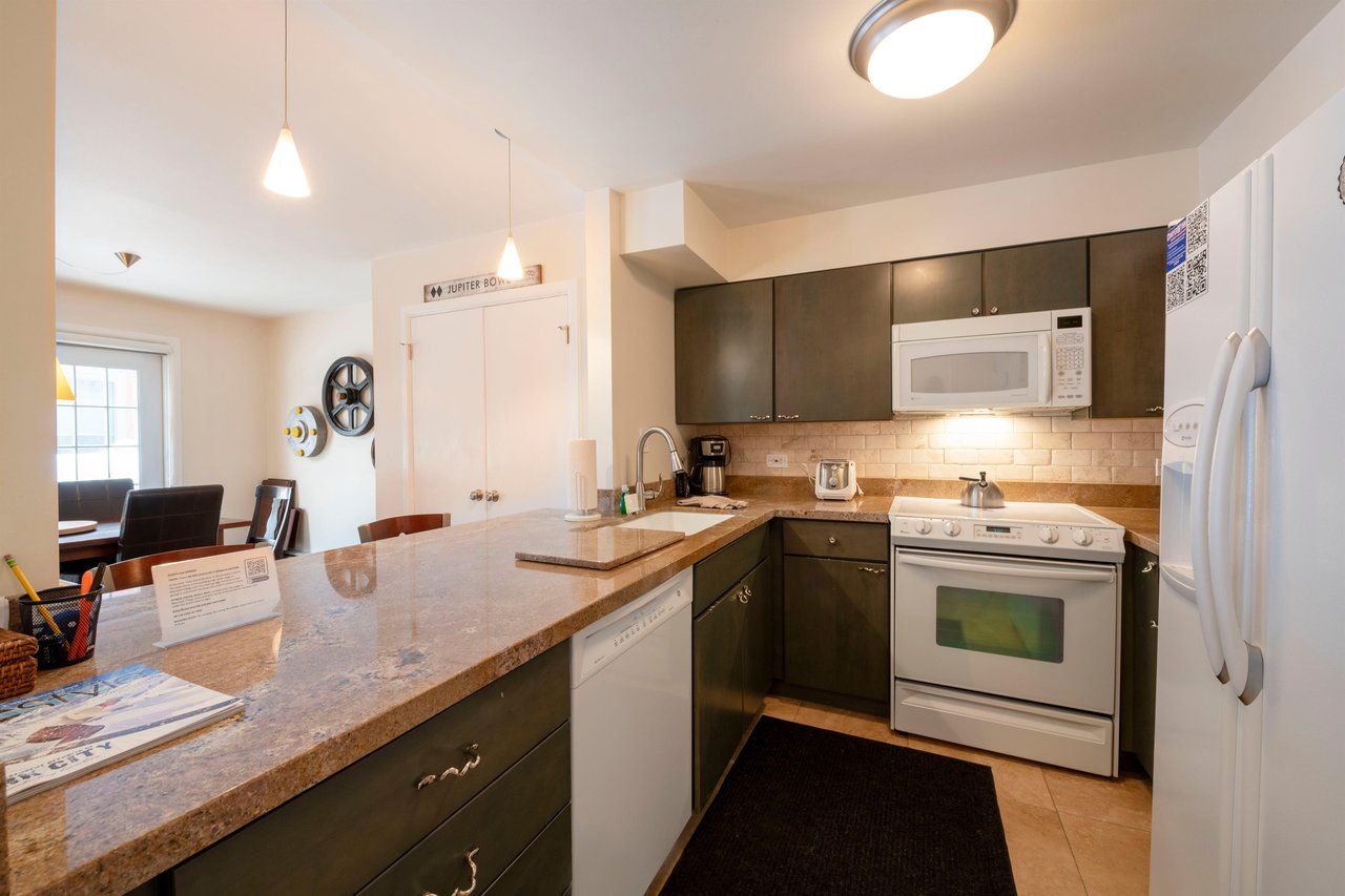 Resort Plaza 5007 has all the comforts of home — this stylish kitchen features sleek dark cabinetry, full appliances, and a convenient breakfast bar perfect for casual mornings before hitting the slop