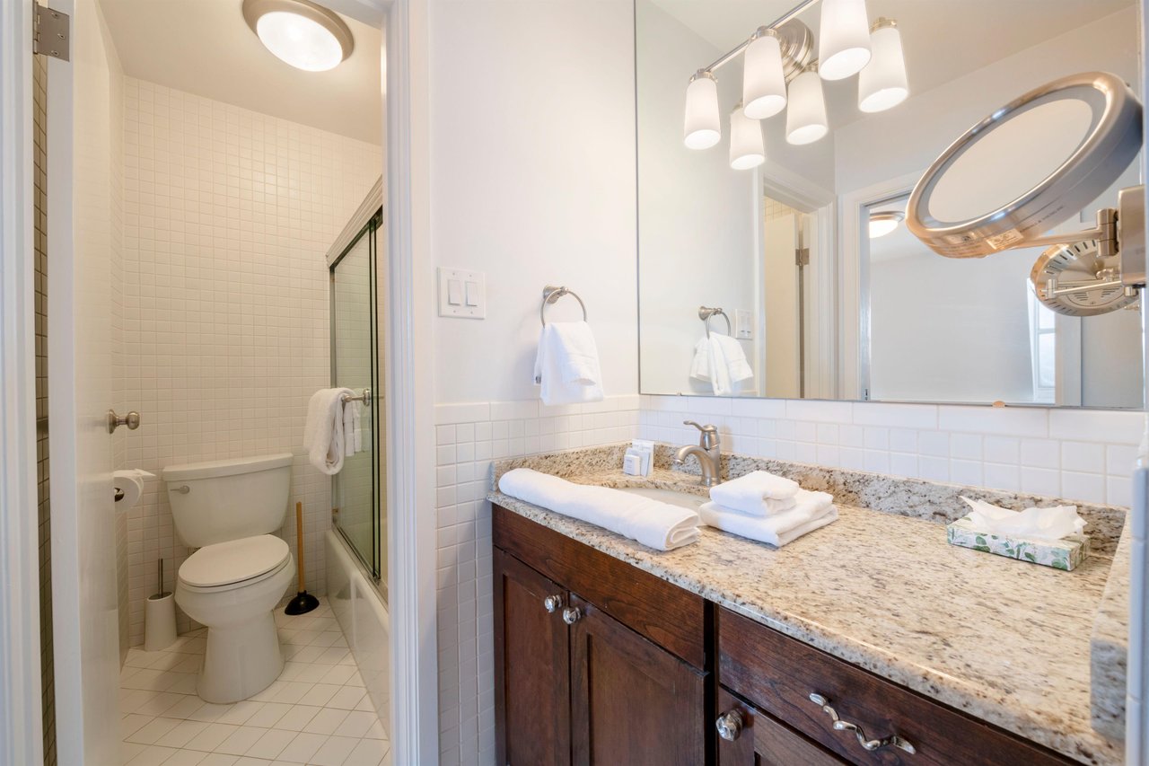 Light and pristine, this beautifully finished bathroom at Resort Plaza 5007 features a granite vanity, rich dark wood cabinetry, and a glassenclosed shower..