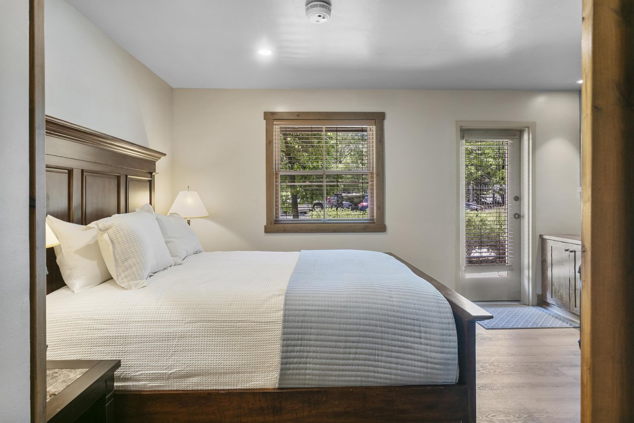 The queen bedroom is bright and simply done — clean linens, natural light, a gas fireplace, and a comfortable place to land after a day on the mountain.