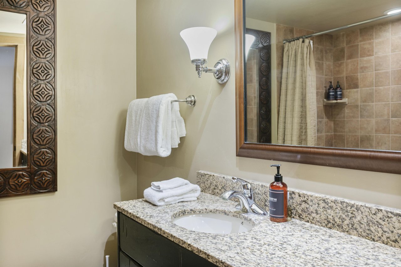 A clean, wellappointed bathroom with a granite vanity, plush towels, and a spacious tiled shower.