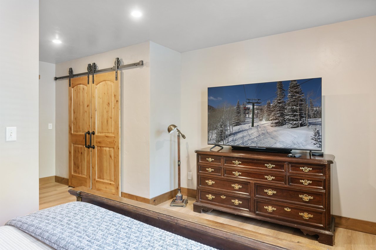 Mountain accents give this bedroom a sense of place — practical storage and a flat screen make it easy to settle in.