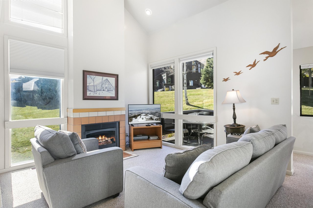 Settle into the warm and inviting living room at Three Kings 41, where a cozy fireplace, comfortable seating, and beautiful golf course views create the perfect atmosphere for relaxing in this classic