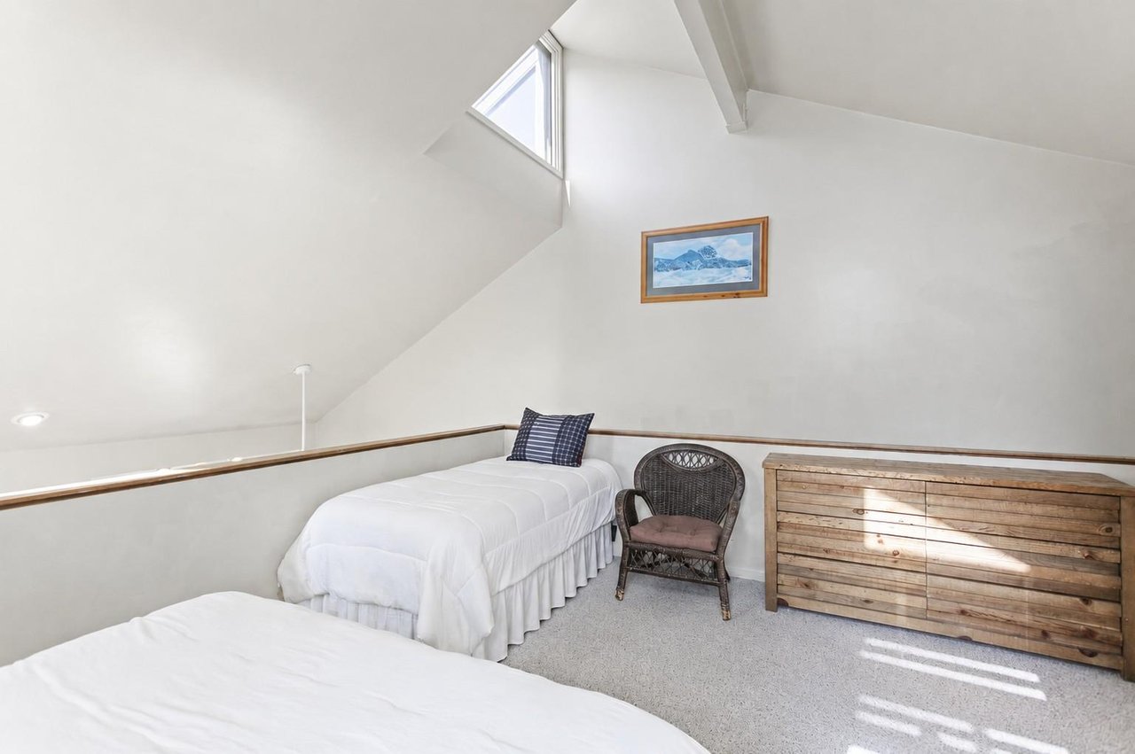 The loft bedroom offers one queen plus one twin bed beneath soaring ceilings, with a skylight bringing in soft natural light — a favorite spot for kids in this Park City condo rental.