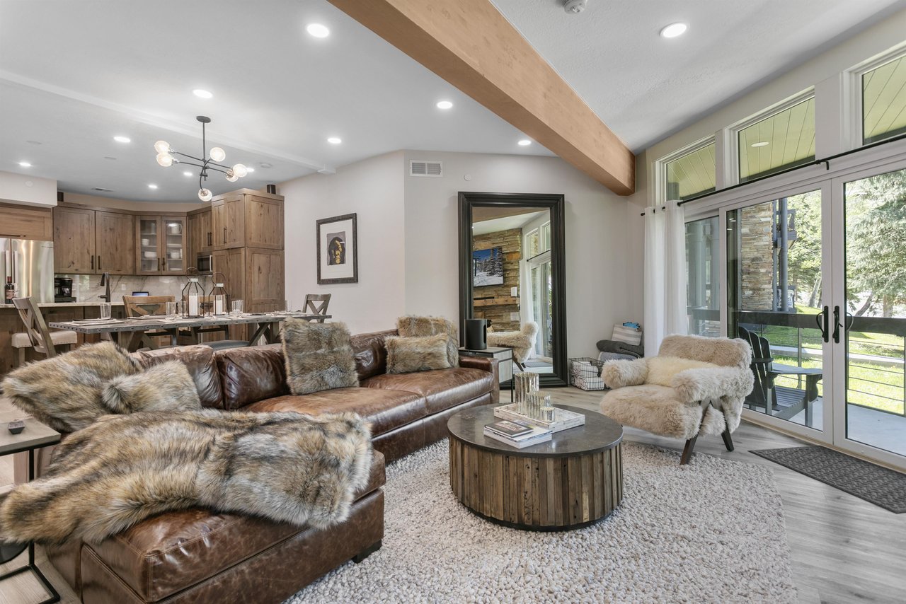 The openconcept living and dining area at Powder Run C13 is designed for entertaining, featuring soaring wood beam ceilings, modern furnishings, and seamless indooroutdoor access — a standout Deer