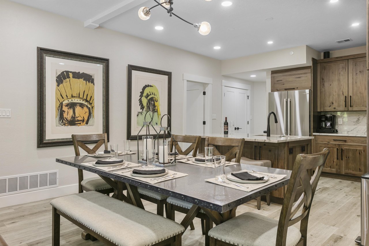 Gather around the elegant dining table at Powder Run C13, where a modern chandelier, mountaininspired décor, and views of the stone fireplace create the perfect setting for memorable meals during yo