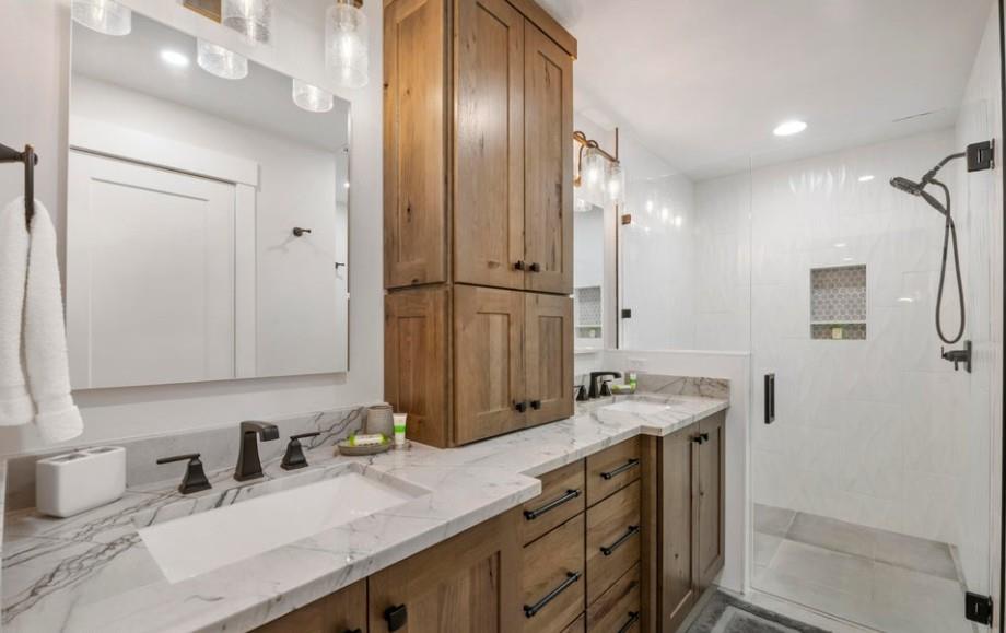 Pamper yourself in the stunning primary bathroom at Powder Run C13, featuring double sinks, luxurious marble countertops, custom wood cabinetry, and a spacious walkin shower — pure elegance in this 