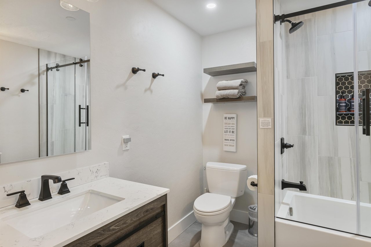 Your private bathroom features a sleek walkin shower with elegant glass doors, plush towels on floating shelves, and modern fixtures in calming neutral tones—designed for your comfort and relaxation.