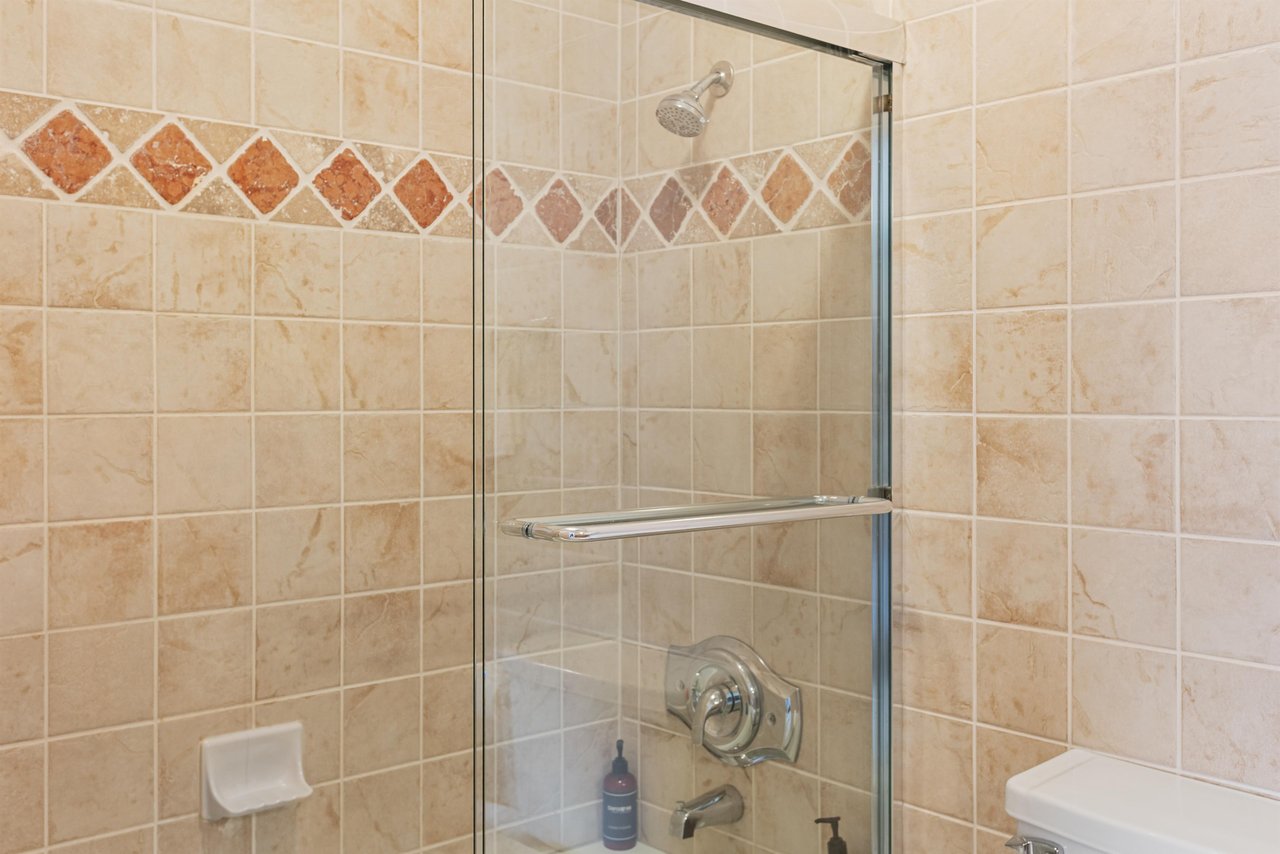 Tiled walkin shower at Resort Plaza 5064s ensuite, framed by a decorative diamond tile accent and a sleek glass door.