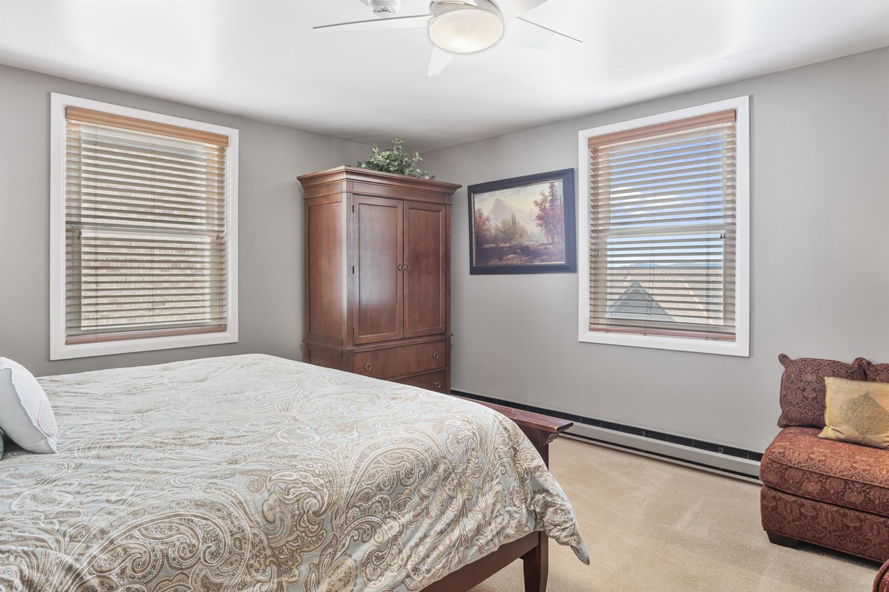 Guest bedroom at Resort Plaza 5064 with a plush king bed, warm wood armoire, and mountain art print for a cozy retreat.