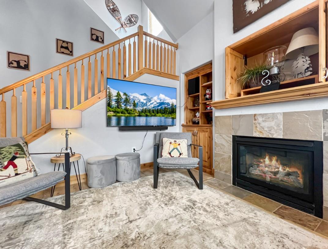 Settle into this inviting living space where rustic charm meets modern comfort. Cozy seating invites you to unwind by the crackling fireplace, while vaulted ceilings and natural light create an airy m