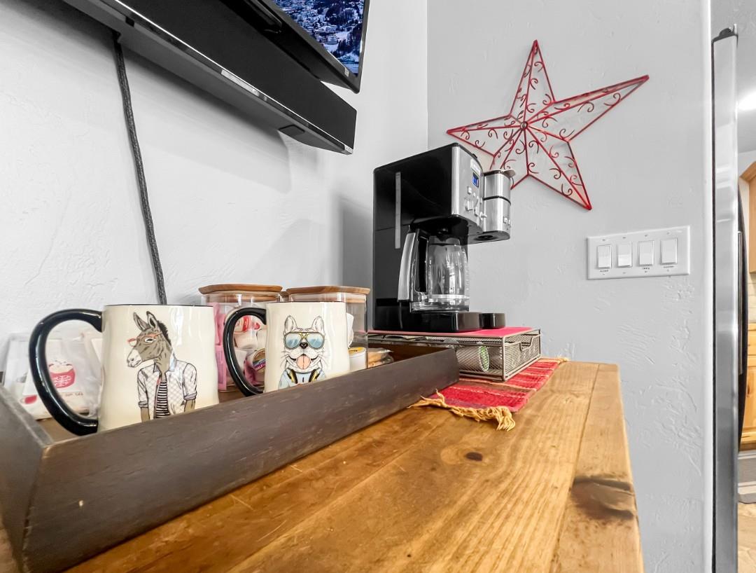 Start your mornings with freshly brewed coffee at this charming station, featuring playful mugs and thoughtful touches like a festive red star accent. The warm wood countertop and quirky decor create 