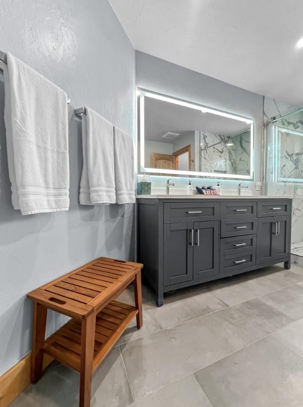 Step into your elegant private bathroom, where crisp white towels await and a spacious vanity offers plenty of room for your morning routine. The soft lighting and modern finishes create a calming spa