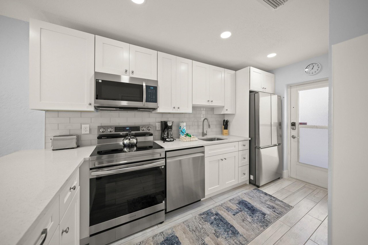 Your fully equipped kitchen features crisp white cabinets, stainless steel appliances, and clean countertops—perfect for preparing homecooked meals during your stay.