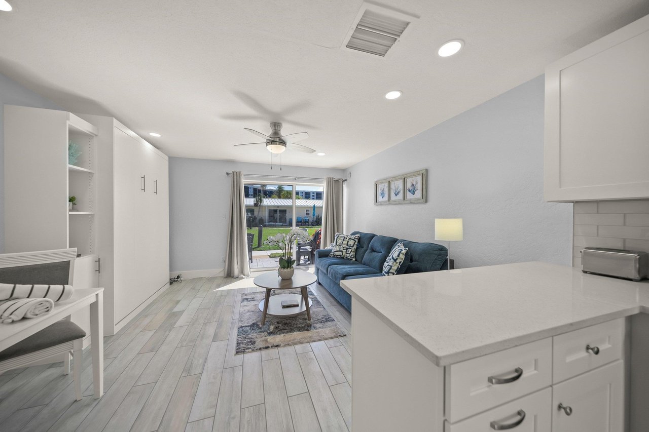 Your stylish openconcept living space flows seamlessly from kitchen to lounge, featuring modern finishes and a cozy blue sofa perfect for relaxation.