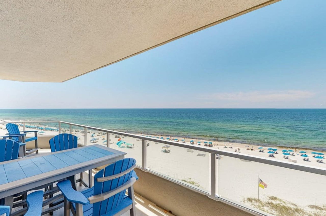 A private balcony with chairs and a table overlooking the beach at Silver Beach
