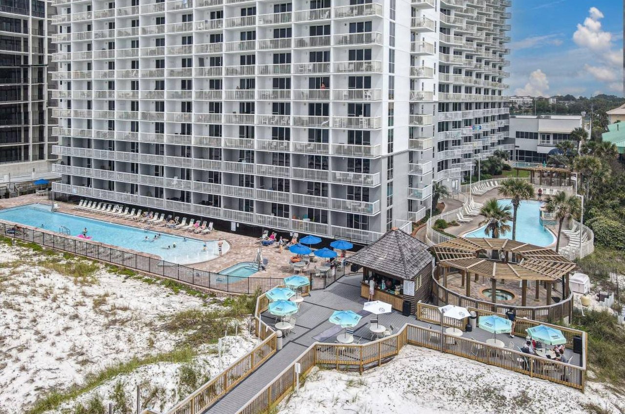 Birds eye view of the pool deck with pools a hot tub and a poolside bar at Pelican Beach Resort