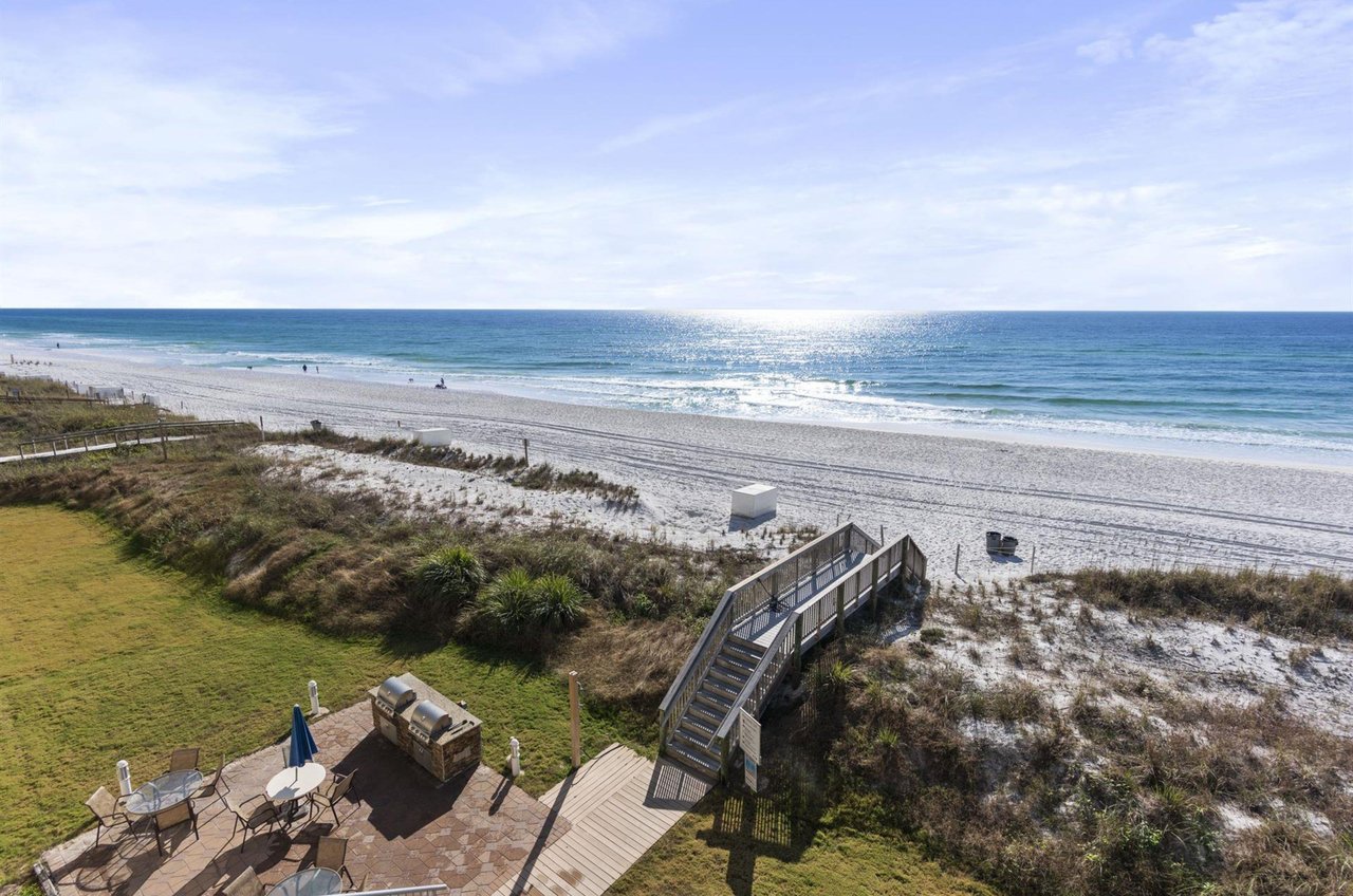 The community has a grilling patio with tables and chairs for picnicing next to a boardwalk to the beach.