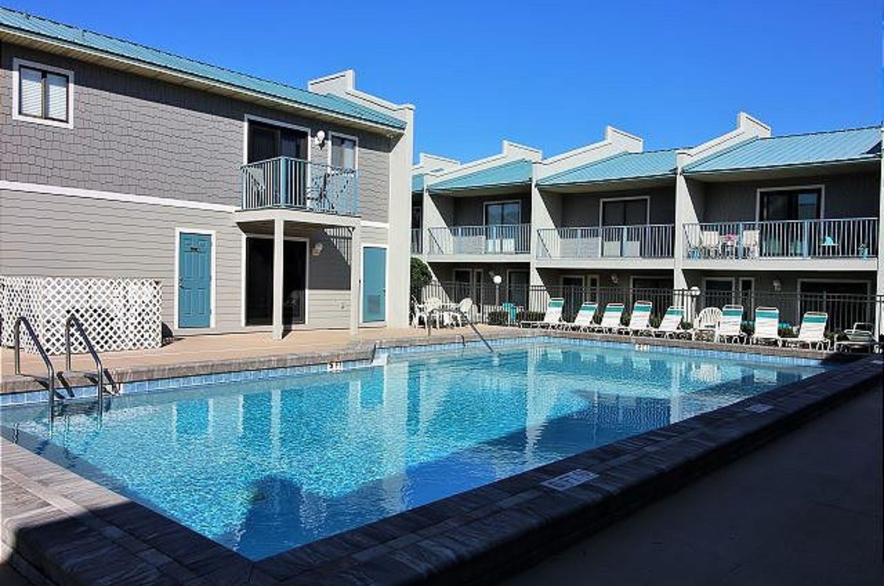 The complexs sparkling swimming pool and sundeck with loungers.