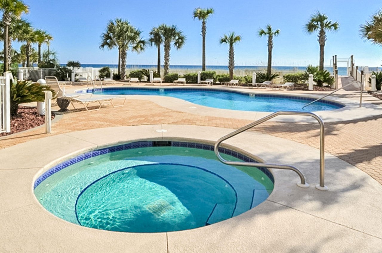 The community hot tub and swimming pool with palm trees and the Gulf of Mexico beyond.