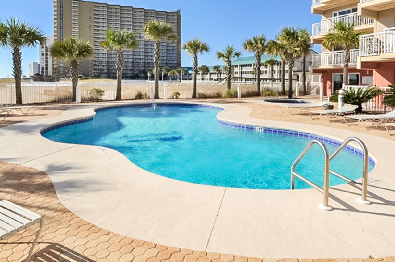 The complexs irregularshaped swimming pool sparkles under blue skies.
