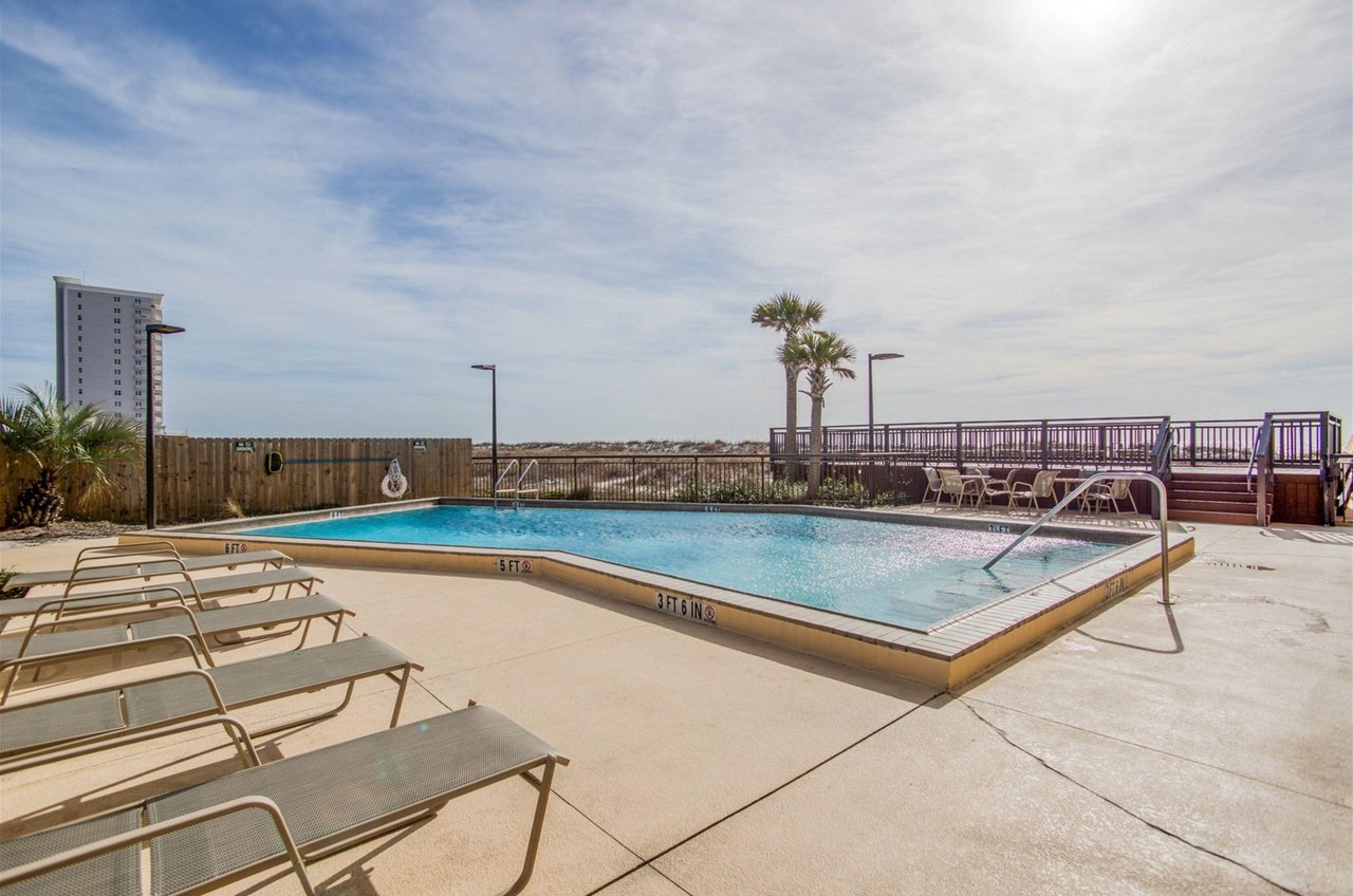 The outdoor pool with lounge chairs overlooking the Gulf at Ocean Breeze West