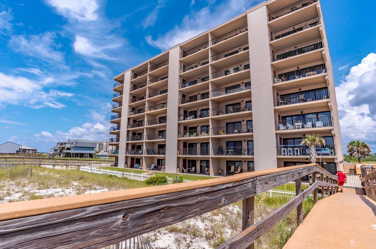 The beachfacing exterior of Ocean Breeze West with a wooden boardwalk leading towards the Gulf